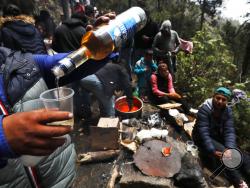 In this Friday, May 3, 2019 photo, a celebrant pours liquor into a plastic cup on the flanks of the Iztacc huatl volcano or The Sleeping Woman (the volcano resembles a reclining female), as part of the Day of the Cross celebrations, near Santiago Xalitzintla, Mexico. The residents of Santiago Xalitzintla celebrate over two days in early May, and leave offerings on an altar at the base of the volcano, asking for a good harvest and as gratitude for harvests past. (AP Photo/Marco Ugarte)