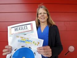 In this photo taken Wednesday, May 15, 2019, Vashon Island High School nurse Sarah Day holds information about measles vaccinations as she poses for a photo in Vashon Island, Wash. 