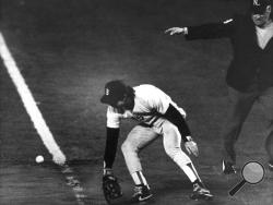 FILE - In this Oct. 25, 1986, file photo, Boston Red Sox first baseman Bill Buckner misplays the ball during during Game 6 of the World Series against the New York Mets. Buckner, a star hitter who became known for making one of the most infamous plays in major league history, has died. He was 69. Buckner's family said in a statement that he died Monday, May 27, 2019, after a long battle with dementia. (Stan Grossfeld/The Boston Globe via AP, File)
