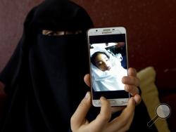 In this Monday, May 27, 2019 photo, Muna Awad, mother of 5-year-old Aisha al-Loulu, shows a photo of her daughter while in a Jerusalem hospital, at the family home in Bureij refugee camp in central Gaza Strip. Instead of a family member, Israeli authorities had approved a stranger to escort Aisha from the blockaded Gaza Strip to the east Jerusalem hospital. As her condition deteriorated, the child was returned to Gaza unconscious. One week later, she was dead. (AP Photo/Hatem Moussa)