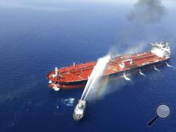 An Iranian navy boat sprays water to extinguish a fire on an oil tanker in the sea of Oman, Thursday, June 13, 2019. Two oil tankers near the strategic Strait of Hormuz came under a suspected attack Thursday, setting one of them ablaze in the latest mysterious assault targeting vessels in a region crucial to global energy supplies amid heightened tension between Iran and the U.S. (AP Photo/Tasnim News Agency)