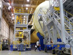 A man walks underneath the core stage for NASA's Space Launch System (SLS), which they say will carry the Orion spacecraft, and ultimately a crew, to the moon and beyond, at the NASA Michoud Assembly Facility in New Orleans, Friday, June 28, 2019. (AP Photo/Gerald Herbert)