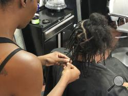 Shana Bonner, left, styles the hair of Pho Gibson at Exquisite U hair salon in Sacramento, Calif., Wednesday, July 3, 2019. Gov. Gavin Newsom signed into law Wednesday a bill making California the first state to ban workplace and school discrimination against black people for wearing hairstyles such as braids, twists and locks. (AP Photo/Kathleen Ronayne)