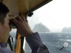 n this April 28, 2005, file photo, a South Korean coast guard looks at Dokdo islets, known as "Takeshima" in Japanese, through a telescope on the patrol ship Sambong-ho on the East Sea, South Korea. South Korean jets fired warning shots after a Russian military plane violated South Korea's airspace on Tuesday, July 23, 2019, Seoul officials said, in the first such incident between the countries. (AP Photo/Ahn Young-joon, File)