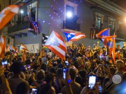 People celebrate outside the governor's mansion La Fortaleza, after Gov. Ricardo Rossello announced that he is resigning Aug. 2 after nearly two weeks of protests and political upheaval touched off by a leak of crude and insulting chat messages between him and his top advisers, in San Juan, Puerto Rico, Thursday, July 25, 2019. (AP Photo/Dennis M. Rivera Pichardo)