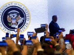 In this July 23, 2019 photo, President Donald Trump takes the stage at Turning Point USA Teen Student Action Summit in Washington. The White House says it had no warning that an altered presidential seal featuring a two-headed eagle clutching golf clubs would be shown at a speech by President Donald Trump this week. (AP Photo/Andrew Harnik)