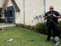 A Los Angeles police officer stands outside of an apartment where a shooting occurred in the Canoga Park area of Los Angeles on Thursday, July 25, 2019. Police say a gunman shot five people, killing three, in two attacks in Los Angeles before he tried to rob someone outside a bank. (Dean Musgrove/The Orange County Register via AP)