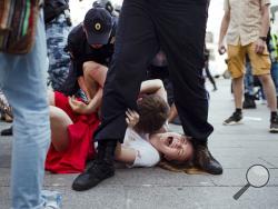 In this photo taken on Saturday, July 27, 2019, Inga Kudracheva screams as her boyfriend Boris Kantorovich lies atop her while police try to detain him during an unsanctioned protest in Moscow. Images of the young couple have been spread on social media. They say the crackdown by police has left them shaken but with their resolve strengthened. (AP Photo/Denis Sinyakov)