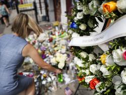 Mourners bring flowers to a makeshift memorial Tuesday, Aug. 6, 2019, for the slain and injured in the Oregon District after a mass shooting that occurred early Sunday morning, in Dayton. (AP Photo/John Minchillo)