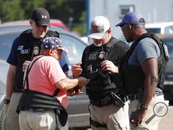 Domingo Candelaria, a registered immigrant, shows federal agents his identification as he prepares to leave the Koch Foods Inc., plant in Morton, Miss., following a raid by U.S. immigration officials, Wednesday, Aug. 7, 2019. The raid, one of several in Mississippi, was part of a large-scale operation targeting owners as well as undocumented employees. (AP Photo/Rogelio V. Solis)