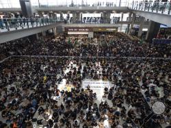 Protesters surround banners that read: "Those on the street today are all warriors!" center top, and "Release all the detainees!" during a sit-in rally at the arrival hall of the Hong Kong International airport in Hong Kong, Monday, Aug. 12, 2019. Hong Kong airport suspends check-in for all remaining flights Monday due to ongoing pro-democracy protest in terminal. (AP Photo/Vincent Thian)