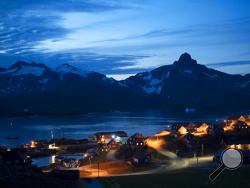 In this photo taken late Friday, Aug. 16, 2019, homes are illuminated after the sunset in Tasiilaq, Greenland. (AP Photo/Felipe Dana)