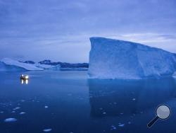 In this Aug. 15, 2019, photo, a boat navigates at night next to icebergs in eastern Greenland. U.S. President Trump announced his decision to postpone a visit to Denmark by tweet on Tuesday Aug. 20, 2019, after Danish Prime Minister Mette Frederiksen dismissed the notion of selling Greenland to the U.S. as "an absurd discussion." (AP Photo/Felipe Dana)