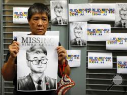 A supporter holds a poster outside of the British Consulate in Hong Kong during a rally in support of an employee of the consulate who was detained while returning from a trip to China, Wednesday, Aug. 21, 2019. China said Wednesday a staffer at the British consulate in Hong Kong has been given 15 days of administrative detention in the city of Shenzhen for violating a law on public order. (AP Photo/Vincent Yu)