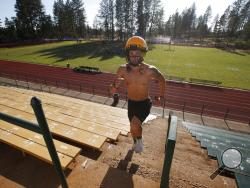 In this Thursday, Aug. 22, 2019, photo, Paradise High School football player Lukas Hartley runs up the stairs of the football stadium after practice in Paradise, Calif. Paradise’s game against Williams High School on Friday will be the first game for the team since a wildfire nearly destroyed the foothill community last year. (AP Photo/Rich Pedroncelli)