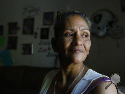 In this photo taken Wednesday, Aug. 14, 2019, Susie Garza who receives a monthly city provided debit card through a trial program, poses in her home in Stockton, Calif. Garza is participating in the Stockton Economic Empowerment Demonstration. The program, which started in February, gives $500 a month to 125 people who earn at or below the median household income of $46,033. They can spend the money with no restrictions. Stockton Mayor Michael Tubbs, who initiated the privately funded program, says it could