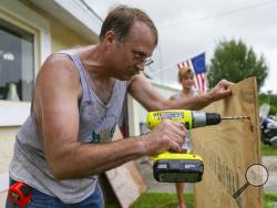 Colin Johnson drills plywood as he prepares to board a window at his father's home in preparation for Hurricane Dorian, Friday, Aug. 30, 2019, in Vero Beach, Fla. Johnson's father, Larry, unexpectedly died Thursday. (Matias J. Ocner/Miami Herald via AP)