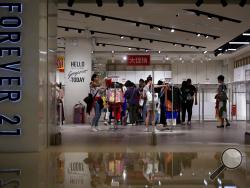 FILE - In this Tuesday, May 7, 2019, file photo, women select clothing at an American fast fashion retailer Forever 21 which is offering clearance discounts at a shopping mall after it pulled out from China's market, in Beijing. Low-price fashion chain Forever 21, a one-time hot destination for teen shoppers that fell victim of its own rapid expansion and changing consumer tastes, announced Sunday, Sept. 29, 2019, that it has filed for Chapter 11 bankruptcy protection. (AP Photo/Andy Wong, File)