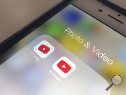 FILE - In this Wednesday, April 25, 2018, file photo, the YouTube app and YouTube Kids app are displayed on a smartphone in New York. A new survey confirms what a lot of parents already know: Teens and tweens are consuming a lot of online video, often on services such as YouTube. (AP Photo/Jenny Kane, File)