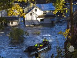 In this photo provided by the New York State Governor's Office, a man looks from a window of a house being flooded by rising waters of the East Canada Creek as police arrive in a rescue boat, Friday, Nov. 1, 2019 in Dolgeville, N.Y. Several hundred people were being evacuated in scattered areas around the state because of high waters. (Darren McGee/New York State Governor's Office via AP)