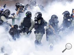 Police in riot gear move through a cloud of smoke as they detain a protester at the Hong Kong Polytechnic University in Hong Kong, Monday, Nov. 18, 2019. Hong Kong police fought off protesters with tear gas and batons Monday as they tried to break through a police cordon that is trapping hundreds of them on a university campus. (AP Photo/Ng Han Guan)