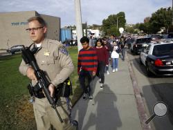 FILE - This Nov. 14, 2019 file photo shows a California Highway Patrol officer escorting students out of Saugus High School after a shooting on the campus in Santa Clarita, Calif. Authorities say the teenager who shot five classmates, killing two, at a Southern California high school used an unregistered "ghost gun." Los Angeles County Sheriff Alex Villanueva Villanueva told media outlets Thursday, Nov. 21, 2019 that Nathaniel Tennosuke Berhow's semi-automatic handgun had been assembled and did not have a s
