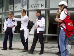 Prof. Alex Wai, second from left, a vice president with the Hong Kong Polytechnic University prepares to lead a team to look for holed up protesters on the university campus in Hong Kong, Tuesday, Nov. 26, 2019.