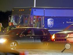 Law enforcement stand near a vehicle that appears to be part of the crime scene where four people were killed, Thursday, Dec. 5, 2019 in Miramar, Fla. The FBI says four people, including a UPS driver, were killed after robbers stole the driver's truck and led police on a chase that ended in gunfire at a busy Florida intersection during rush hour. (Charles Trainor Jr./Miami Herald via AP)