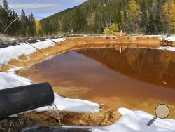 FILE - In this Oct. 12, 2018 file photo, water contaminated with arsenic, lead and zinc flows from a pipe out of the Lee Mountain mine and into a holding pond near Rimini, Mont. The community is part of the Upper Tenmile Creek Superfund site, where dozens of abandoned mines have left water supplies polluted and residents must use bottled water. The Trump administration has built up the largest backlog of unfunded toxic Superfund projects awaiting clean-up in at least 15 years, nearly tripling the number of 