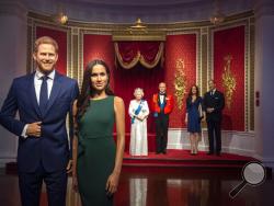 The figures of Britain's Prince Harry and Meghan, Duchess of Sussex, left, are moved from their original positions next to Queen Elizabeth II, Prince Philip and Prince William and Kate, Duchess of Cambridge, at Madame Tussauds in London, Thursday Jan. 9, 2020. Madame Tussauds moved its figures of Prince Harry and Meghan, Duchess of Sussex from its Royal Family set to elsewhere in the attraction. (Victoria Jones/PA via AP)