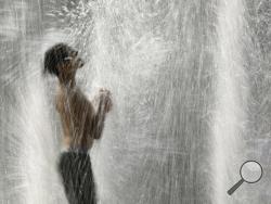 FILE - In this July 18, 2019, file photo, a boy plays in a fountain to cool off as temperatures approach 100 degrees Fahrenheit (38 Celsius) in Kansas City, Mo. The decade that just ended was by far the hottest ever measured on Earth, capped off by the second-warmest year on record, NASA and the National Oceanic and Atmospheric Administration reported Wednesday, Jan. 15, 2020. (AP Photo/Charlie Riedel, File)