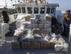 FILE - In this Aug. 29, 2019, file photo, members of the Coast Guard stand near seized cocaine in Los Angeles. The nation's drug addiction crisis has been morphing in a deadly new direction: more Americans struggling with meth and cocaine. Now the government will allow states to use federal money earmarked of the opioid crisis to help people addicted to those drugs as well. The change to a $1.5 billion opioid grants program was buried in a massive spending bill that Congress passed late in 2019. (AP Photo/C