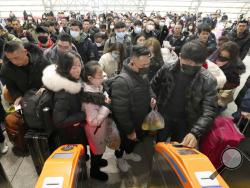 Travelers wear face masks as they line up at turnstiles at a train station in Nantong, eastern China's Jiangsu province, Wednesday, Jan. 22, 2020. The number of cases of a new virus has risen to over 400 in China and the death toll to 9, Chinese health authorities said Wednesday. (Chinatopix via AP)