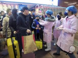 Medical workers use an infrared thermometer to check travelers at a train station in Nanchang in southern China's Jiangxi Province, Wednesday, Jan. 22, 2020. Chinese health authorities urged people in the city of Wuhan to avoid crowds and public gatherings, after warning that a new viral illness that has infected more than 400 people and killed at least nine could spread further. (Chinatopix via AP)