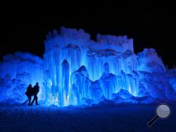 FILE – In this Saturday, Jan. 26, 2019 file photo, a couple heads toward an entrance to a cavern at Ice Castles in North Woodstock, N.H. A neighbor to the seasonal atraction alleges that melt water from the Ice Castles' property flooded her basement with over 15,000 gallons of water in April 2019. (AP Photo/Robert F. Bukaty, File)