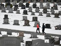 FILE - In this Friday, Jan. 24, 2020 file photo, two joggers run through Grandview Cemetery in Johnstown, Pa. Data released on Thursday, Jan. 30, 2020 shows that U.S. life expectancy has improved for the first time in four years, thanks to a sharp decline in the cancer death rate and to a drop in fatal drug overdoses. (Todd Berkey/The Tribune-Democrat via AP)