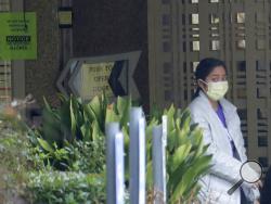 A person wearing a mask walks past a sign banning visitors at the Life Care Center in Kirkland, Wash., near Seattle, Monday, March 2, 2020. Dozens of people associated with the facility are reportedly ill with respiratory symptoms or hospitalized and are being tested for the COVID-19 virus. (AP Photo/Ted S. Warren)