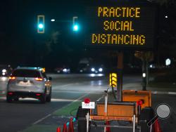 FILE - In this Wednesday, March 18, 2020 file photo, a sign reminding people about "social distancing" in the midst of the COVID-19 coronavirus outbreak stands next to a roadway in North Vancouver, British Columbia, Canada. Many see “social distancing” to be the greatest pandemic-era addition the vernacular yet — easily understood phrasing that’s helped communicate to millions that they need to keep a safe berth to avoid spreading the virus. (Jonathan Hayward/The Canadian Press via AP)