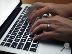 FILE - This June 19, 2017 file photo shows a person working on a laptop in North Andover, Mass. Many now are working and studying from home to limit the spread of the new coronavirus, one that's testing how productive people can be in a pandemic. It's also challenging the capacity of the internet, home Wi-Fi systems and video-chat services amid unprecedented demand. (AP Photo/Elise Amendola, File)