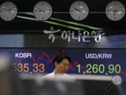 A currency trader walks by screens showing the Korea Composite Stock Price Index (KOSPI), left, and the foreign exchange rate between U.S. dollar and South Korean won at the foreign exchange dealing room in Seoul, South Korea, Tuesday, March 24, 2020. Asian stock markets gained Tuesday after the U.S. Federal Reserve promised support to the struggling economy as Congress delayed action on a $2 trillion coronavirus aid package. (AP Photo/Lee Jin-man)