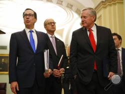 Treasury Secretary Steven Mnuchin, left, accompanied by White House Legislative Affairs Director Eric Ueland and acting White House chief of staff Mark Meadows, speaks with reporters as he walks to the offices of Senate Majority Leader Mitch McConnell of Ky. on Capitol Hill in Washington, Tuesday, March 24, 2020. (AP Photo/Patrick Semansky)