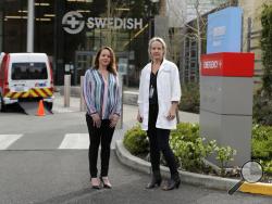 In this Tuesday, March 24, 2020, photo, Melissa Short, left, system executive director for women's health at Swedish Medical Center, and Dr. Tanya Sorensen, a practicing maternal fetal medicine physician at Swedish, and executive director for women's services, pose in front of the center in Edmonds, Wash., north of Seattle. Several dozen expectant moms who had planned to give birth at the birth unit of the center will now have to go elsewhere because the facility is being repurposed to treat victims of the 