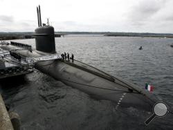 In this July 13, 2007 file photo, French Marine officers wait atop "Le Vigilant" nuclear submarine at L'Ile Longue military base, near Brest, Brittany. Stealthily cruising the ocean deeps, deliberately hiding from the world now in turmoil, the crews of nuclear-armed submarines may be among the last pockets of people anywhere who are still blissfully unaware of how the coronavirus pandemic is turning life upside down. The new coronavirus causes mild or moderate symptoms for most people, but for some, especia