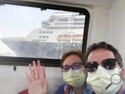 In this March 28, 2020 photo provided by Juan Huergo, Laura Gabaroni and her husband Juan Huergo take a selfie on board a tender after they were evacuated from the Zaandam, a Holland American cruise ship, near the Panama Canal. The Orlando- area couple was transferred to the Rotterdam, together with others who were deemed healthy. Four people have died on board the Zaandam and many others have are suffering from flu-like symptoms. (Juan Huergo via AP)