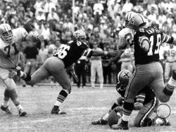 FILE - In this Nov. 8, 1970, file photo, New Orleans Saints' Tom Dempsey (19) moves up to kick a 63-yard field goal as teammate Joe Scarpati holds the ball and Detroit Lions' Alex Karras (71) rushes in while Saints' Bill Cody (66) blocks, in New Orleans. Dempsey, who played in the NFL despite being born without toes on his kicking foot and made a record 63-yard field goal, died late Saturday, April 4, 2020, in New Orleans while struggling with complications from the new coronavirus, his daughter said. He wa