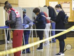 An election official cleans a voting booth before a person votes at Riverside High School, in Milwaukee on Tuesday, April 7, 2020. The Wisconsin primary is moving forward in the wake of the coronavirus epidemic after Gov. Tony Evers sought to shut down Tuesday's election in a historic move Monday that was swiftly rejected by the conservative majority of the Wisconsin Supreme Court by the end of the day. (Mike De Sisti/Milwaukee Journal-Sentinel via AP)