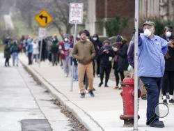 In this April 7, 2020, photo, voters masked against coronavirus line up at Riverside High School for Wisconsin's primary election in Milwaukee. The devastating coronavirus pandemic stands poised to reshape the political map this November. The virus has pummeled battleground states and alarmed Republicans who see early warning signs for an election that could be a referendum on President Donald Trump’s management of the crisis. (AP Photo/Morry Gash)