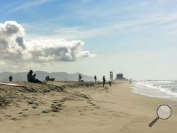 People relax on the sand at Hueneme Beach at Port Hueneme, Calif., on Sunday, April, 19, 2020, after it reopened with restrictions following a closure due to the coronavirus pandemic. It was among beaches and parks that became available to the public in Ventura County, northwest of Los Angeles. Parking was limited to reduce attendance and facilities such as the pier, picnic tables and other developed sites remained off limits. (AP Photo/John Antczak)