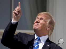 FILE - In this Aug. 21, 2017, file photo, President Donald Trump points to the sun as he arrives to view the solar eclipse at the White House in Washington. Trump's comment about injecting disinfectant to fight coronavirus is just the latest in a long list of comments and actions that run contrary to mainstream science. He's gone against scientific and medical advice by staring at an eclipse without protection, calling climate change a hoax and saying wind turbines cause cancer. (AP Photo/Andrew Harnik, Fil