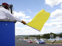 FILE - In this Aug. 6, 2016, file photo, a track marshall waves a yellow caution flag during a NASCAR Xfinity series auto race at Watkins Glen International in Watkins Glen, N.Y. As NASCAR speeds back to the race track during the coronavirus pandemic the series has a heavy responsibility to set a safety standard that doesn't slow the return of other sports. (AP Photo/Mel Evans, File)